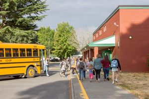 Image: School bus and students in front of a school building